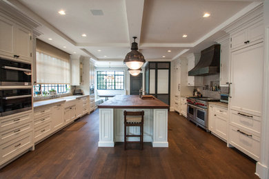 Inspiration for a mid-sized timeless u-shaped dark wood floor open concept kitchen remodel in Los Angeles with a farmhouse sink, shaker cabinets, white cabinets, marble countertops, stone slab backsplash and an island