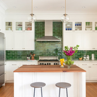 Example of a mid-sized transitional u-shaped medium tone wood floor and brown floor kitchen design in San Francisco with an undermount sink, shaker cabinets, white cabinets, green backsplash, subway tile backsplash, stainless steel appliances, an island and marble countertops