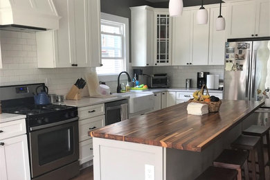 Enclosed kitchen - mid-sized transitional l-shaped enclosed kitchen idea in New York with a farmhouse sink, shaker cabinets, quartz countertops, subway tile backsplash and an island
