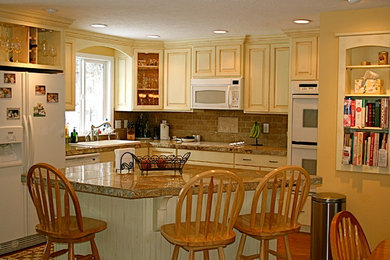 Foto de cocina comedor clásica con armarios con paneles con relieve y una isla