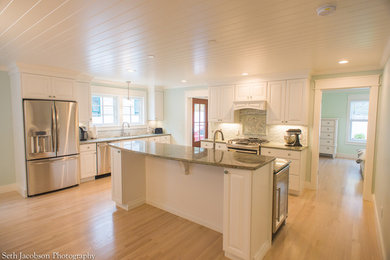 Inspiration for a large coastal u-shaped light wood floor eat-in kitchen remodel in Providence with raised-panel cabinets, white cabinets, quartz countertops, gray backsplash, glass sheet backsplash, stainless steel appliances and an island