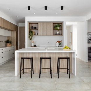 Photo of a contemporary l-shaped kitchen in Geelong with an undermount sink, flat-panel cabinets, light wood cabinets, grey splashback, panelled appliances, with island, beige floor and white benchtop.