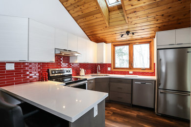 Large modern u-shaped kitchen/diner in Toronto with a submerged sink, flat-panel cabinets, white cabinets, engineered stone countertops, red splashback, glass tiled splashback, stainless steel appliances, medium hardwood flooring, a breakfast bar and white worktops.