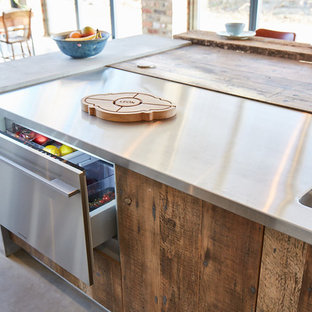Offene, Große Industrial Küche mit Unterbauwaschbecken, flächenbündigen Schrankfronten, hellbraunen Holzschränken, Zink-Arbeitsplatte, Küchenrückwand in Grau, Küchengeräten aus Edelstahl, Betonboden, Halbinsel, grauem Boden und grauer Arbeitsplatte in Sonstige