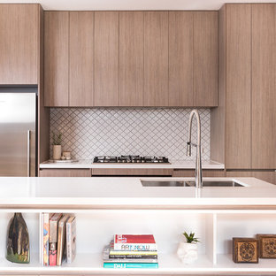 Inspiration for a contemporary galley kitchen in Melbourne with a double-bowl sink, flat-panel cabinets, medium wood cabinets, white splashback, mosaic tile splashback, stainless steel appliances, medium hardwood floors, with island, brown floor and white benchtop.