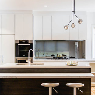 This is an example of a mid-sized contemporary l-shaped open plan kitchen in Melbourne with an undermount sink, flat-panel cabinets, dark wood cabinets, quartz benchtops, metallic splashback, mirror splashback, stainless steel appliances, light hardwood floors, with island, yellow floor and multi-coloured benchtop.