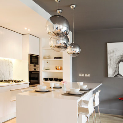Inspiration for a mid-sized contemporary single-wall light wood floor eat-in kitchen remodel in London with an undermount sink, flat-panel cabinets, white cabinets, solid surface countertops, gray backsplash, marble backsplash, stainless steel appliances and a peninsula
