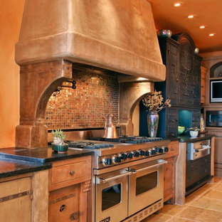 Kitchen - southwestern kitchen idea in Boston with stainless steel appliances, distressed cabinets, brown backsplash and mosaic tile backsplash