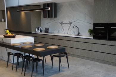 This is an example of a kitchen in Melbourne with a built-in sink, marble splashback, black appliances, porcelain flooring, an island and grey floors.