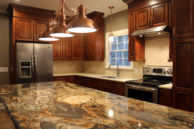 Example of a large classic l-shaped ceramic tile open concept kitchen design in Other with an undermount sink, raised-panel cabinets, medium tone wood cabinets, granite countertops, beige backsplash, stainless steel appliances and an island