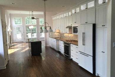 Eat-in kitchen - large traditional single-wall dark wood floor eat-in kitchen idea in New York with an undermount sink, shaker cabinets, white cabinets, granite countertops, gray backsplash, mosaic tile backsplash, stainless steel appliances and an island