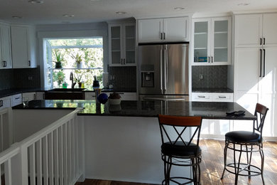 Example of a mid-sized transitional l-shaped medium tone wood floor open concept kitchen design in Portland with a farmhouse sink, shaker cabinets, white cabinets and stainless steel appliances
