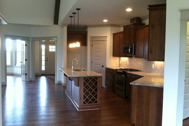 Inspiration for a traditional kitchen/diner in Raleigh with a submerged sink, shaker cabinets, dark wood cabinets, granite worktops, grey splashback, ceramic splashback, stainless steel appliances, dark hardwood flooring and an island.