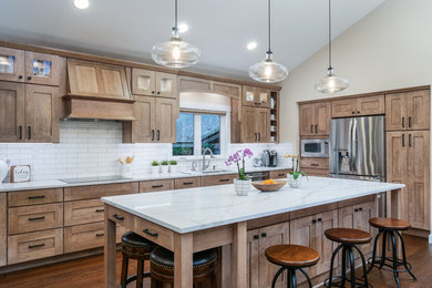Inspiration for a large transitional l-shaped medium tone wood floor and brown floor open concept kitchen remodel in Seattle with an undermount sink, shaker cabinets, light wood cabinets, quartz countertops, white backsplash, porcelain backsplash, stainless steel appliances, an island and white countertops