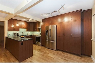 Mid-sized transitional u-shaped light wood floor kitchen pantry photo in Vancouver with an undermount sink, shaker cabinets, medium tone wood cabinets, soapstone countertops, blue backsplash, glass tile backsplash, stainless steel appliances and a peninsula