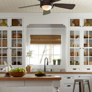 This is an example of a small country galley separate kitchen in New York with an undermount sink, open cabinets, white cabinets, wood benchtops, white splashback, cement tile splashback, stainless steel appliances, medium hardwood floors and with island.