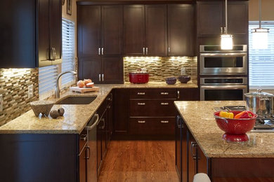 Large transitional l-shaped medium tone wood floor eat-in kitchen photo in Denver with an undermount sink, shaker cabinets, dark wood cabinets, laminate countertops, beige backsplash, glass sheet backsplash, stainless steel appliances and an island