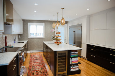 Inspiration for a mid-sized contemporary galley orange floor and medium tone wood floor enclosed kitchen remodel in Montreal with an integrated sink, flat-panel cabinets, white cabinets, marble countertops, stainless steel appliances, an island, white countertops, white backsplash and subway tile backsplash