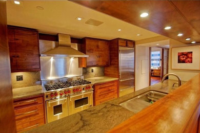 Example of a mid-sized classic galley ceramic tile enclosed kitchen design in Philadelphia with a double-bowl sink, flat-panel cabinets, medium tone wood cabinets, stone slab backsplash, stainless steel appliances and no island