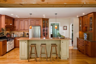 Cette photo montre une cuisine chic en U et bois brun avec un placard avec porte à panneau surélevé, une crédence beige et un électroménager en acier inoxydable.