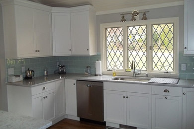 Example of a mid-sized classic l-shaped medium tone wood floor kitchen design in Boston with a drop-in sink, recessed-panel cabinets, white cabinets, blue backsplash, stainless steel appliances and an island