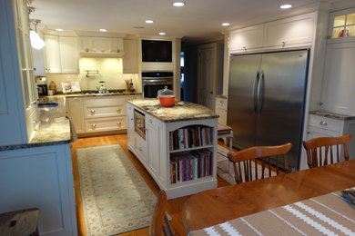 Inspiration for a mid-sized cottage u-shaped light wood floor eat-in kitchen remodel in Boston with an undermount sink, shaker cabinets, white cabinets, granite countertops, stainless steel appliances and an island