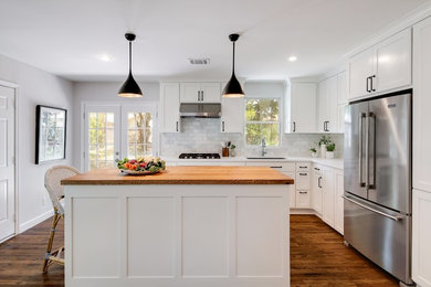 Mid-sized elegant l-shaped medium tone wood floor and brown floor enclosed kitchen photo in Austin with an undermount sink, shaker cabinets, white cabinets, wood countertops, gray backsplash, marble backsplash, stainless steel appliances, an island and brown countertops