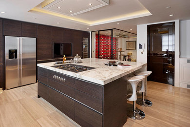 Moderne Küche mit flächenbündigen Schrankfronten, dunklen Holzschränken und Küchengeräten aus Edelstahl in London