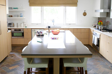 Foto på ett mellanstort funkis kök, med en undermonterad diskho, släta luckor, skåp i ljust trä, bänkskiva i kvarts, grått stänkskydd, rostfria vitvaror, skiffergolv och en köksö