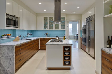 Mid-sized trendy galley porcelain tile and white floor kitchen pantry photo in New York with a double-bowl sink, recessed-panel cabinets, white cabinets, quartzite countertops, blue backsplash, glass tile backsplash, stainless steel appliances and an island