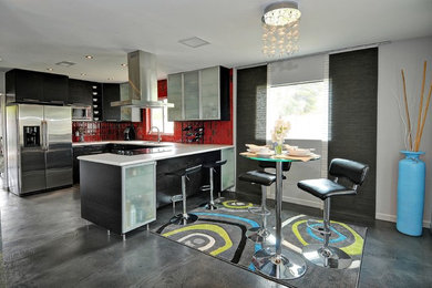 Imagen de cocina contemporánea con armarios con paneles lisos, puertas de armario negras, salpicadero rojo y electrodomésticos de acero inoxidable