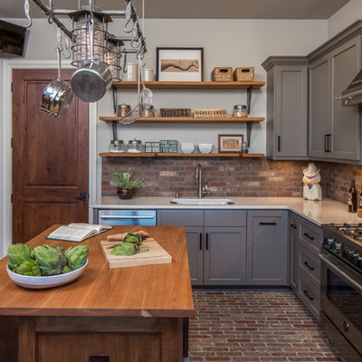 Large transitional l-shaped brick floor and brown floor enclosed kitchen photo in Austin with an undermount sink, gray cabinets, solid surface countertops, stainless steel appliances, an island, shaker cabinets, brick backsplash and brown backsplash