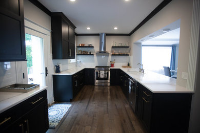 Inspiration for a mid-sized transitional u-shaped dark wood floor and brown floor enclosed kitchen remodel in St Louis with an undermount sink, shaker cabinets, black cabinets, quartz countertops, white backsplash, subway tile backsplash, stainless steel appliances and no island