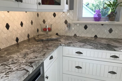Small transitional u-shaped vinyl floor and white floor enclosed kitchen photo in Toronto with a drop-in sink, beaded inset cabinets, white cabinets, granite countertops, white backsplash, porcelain backsplash, stainless steel appliances, no island and gray countertops