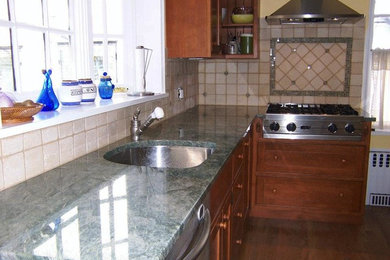 Mid-sized elegant l-shaped kitchen photo in New York with an undermount sink, medium tone wood cabinets, granite countertops, beige backsplash, ceramic backsplash and stainless steel appliances