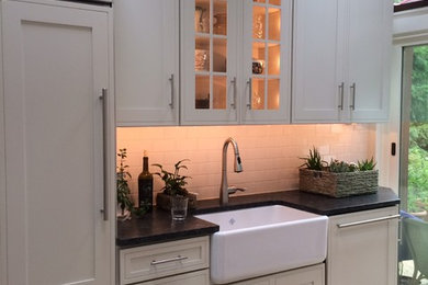 Example of a small transitional galley porcelain tile eat-in kitchen design in Wilmington with a farmhouse sink, shaker cabinets, white cabinets, granite countertops, white backsplash, subway tile backsplash, stainless steel appliances and an island