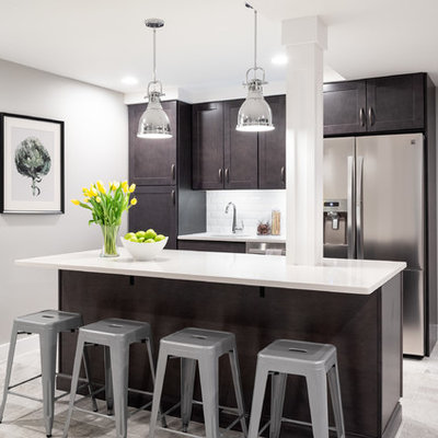 Example of a transitional galley gray floor kitchen design in Philadelphia with an undermount sink, shaker cabinets, dark wood cabinets, white backsplash, stainless steel appliances, an island and white countertops