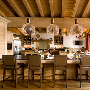 Inspiration pour une grand cuisine américaine chalet en U avec un placard sans porte, des portes de placard en bois brun, une crédence verte, une crédence en carrelage métro, un électroménager en acier inoxydable, un sol en bois brun et un îlot central.