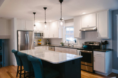 Mid-sized transitional l-shaped light wood floor and brown floor enclosed kitchen photo in Chicago with a double-bowl sink, shaker cabinets, white cabinets, granite countertops, white backsplash, subway tile backsplash, stainless steel appliances and an island