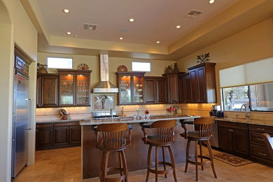 Example of a large transitional u-shaped eat-in kitchen design in Phoenix with dark wood cabinets, stainless steel appliances and an island
