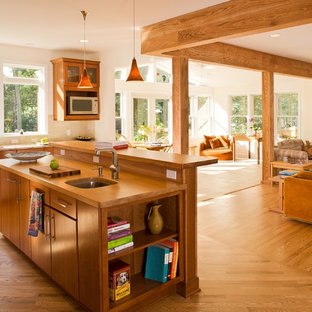 Foto di una cucina tradizionale di medie dimensioni con ante lisce, ante in legno scuro, top in legno, lavello sottopiano, paraspruzzi beige, paraspruzzi con piastrelle in pietra, elettrodomestici in acciaio inossidabile, pavimento in legno massello medio e isola
