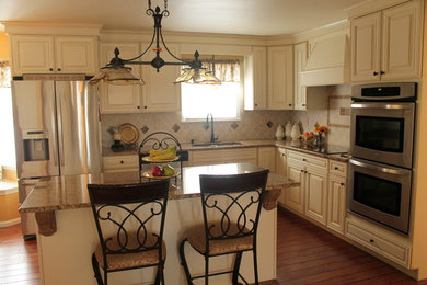 Klassische Wohnküche in L-Form mit Unterbauwaschbecken, Granit-Arbeitsplatte, Küchengeräten aus Edelstahl, profilierten Schrankfronten und braunem Holzboden in Philadelphia