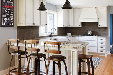 Eat-in kitchen - large traditional u-shaped light wood floor eat-in kitchen idea in Minneapolis with a farmhouse sink, recessed-panel cabinets, white cabinets, granite countertops, brown backsplash, ceramic backsplash, stainless steel appliances and a peninsula
