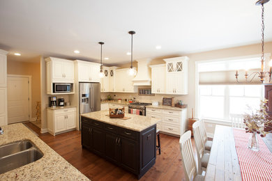 Example of an u-shaped eat-in kitchen design in Chicago with raised-panel cabinets, white cabinets, stainless steel appliances and an island