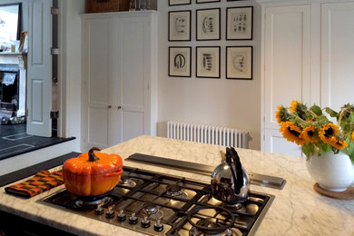 ロンドンにある高級な小さなヴィクトリアン調のおしゃれなキッチン (エプロンフロントシンク、シェーカースタイル扉のキャビネット、青いキャビネット、大理石カウンター、石スラブのキッチンパネル、シルバーの調理設備、塗装フローリング) の写真