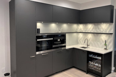 Eat-in kitchen - mid-sized l-shaped light wood floor and beige floor eat-in kitchen idea in DC Metro with an undermount sink, flat-panel cabinets, gray cabinets, quartz countertops, white backsplash, cement tile backsplash, stainless steel appliances, an island and white countertops