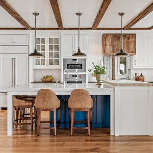 Ispirazione per un ampio cucina con isola centrale costiero con lavello sottopiano, ante in stile shaker, ante bianche, top in quarzo composito, paraspruzzi bianco, paraspruzzi in lastra di pietra, pavimento in legno massello medio, top bianco e elettrodomestici da incasso