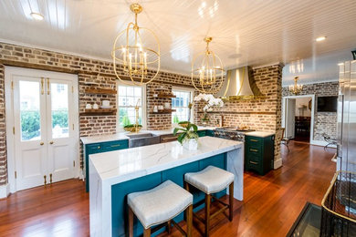 Inspiration for a mid-sized transitional medium tone wood floor and brown floor kitchen pantry remodel in Charleston with a farmhouse sink, beaded inset cabinets, green cabinets, quartz countertops, brown backsplash, brick backsplash, stainless steel appliances, an island and white countertops