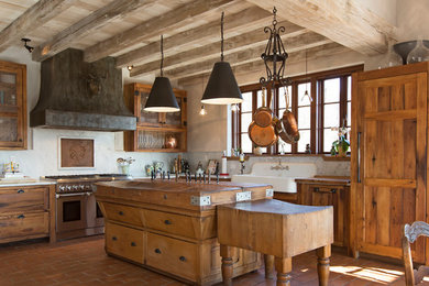 Eat-in kitchen - mid-sized cottage l-shaped terra-cotta tile and red floor eat-in kitchen idea with a farmhouse sink, shaker cabinets, distressed cabinets, white backsplash, stone slab backsplash, paneled appliances, an island, marble countertops and white countertops