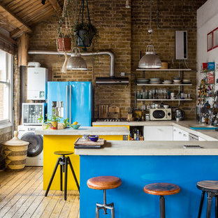 Imagen de cocina en U, bohemia, con armarios con paneles lisos, puertas de armario amarillas, salpicadero de ladrillos, electrodomésticos de colores, suelo de madera clara, dos o más islas, suelo beige y encimeras beige